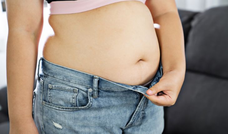 mulher tentando vestir calça jeans após bypass gástrico